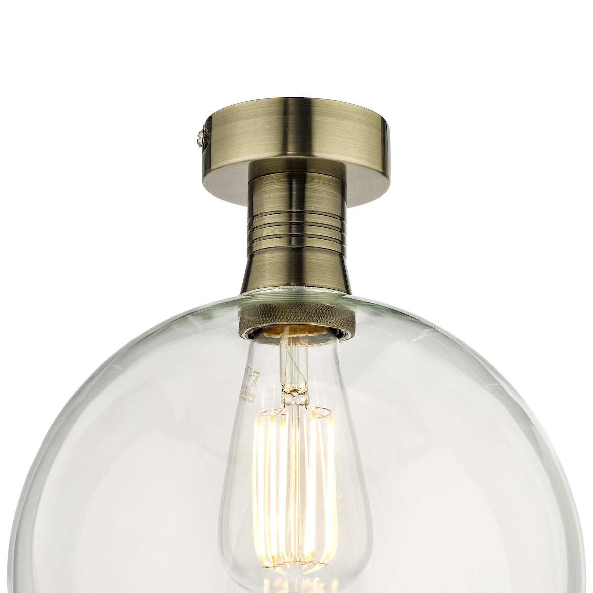 Close-up of a clear glass dome light fixture with a brass base and an exposed filament bulb.