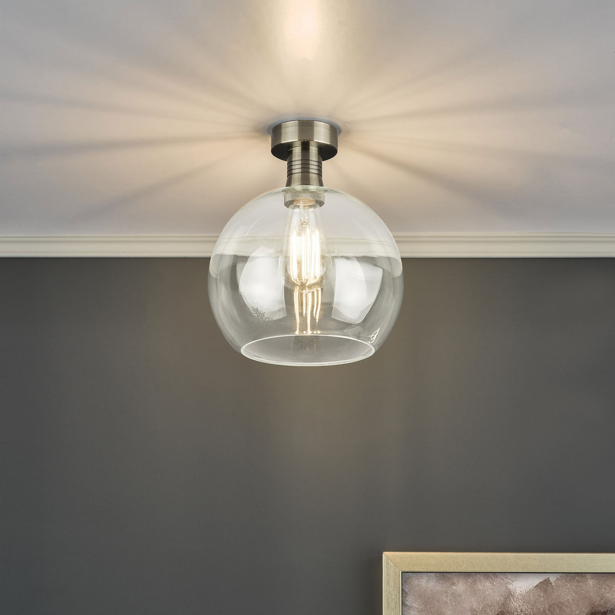 A clear glass globe ceiling light with a brushed nickel base and an exposed filament bulb.