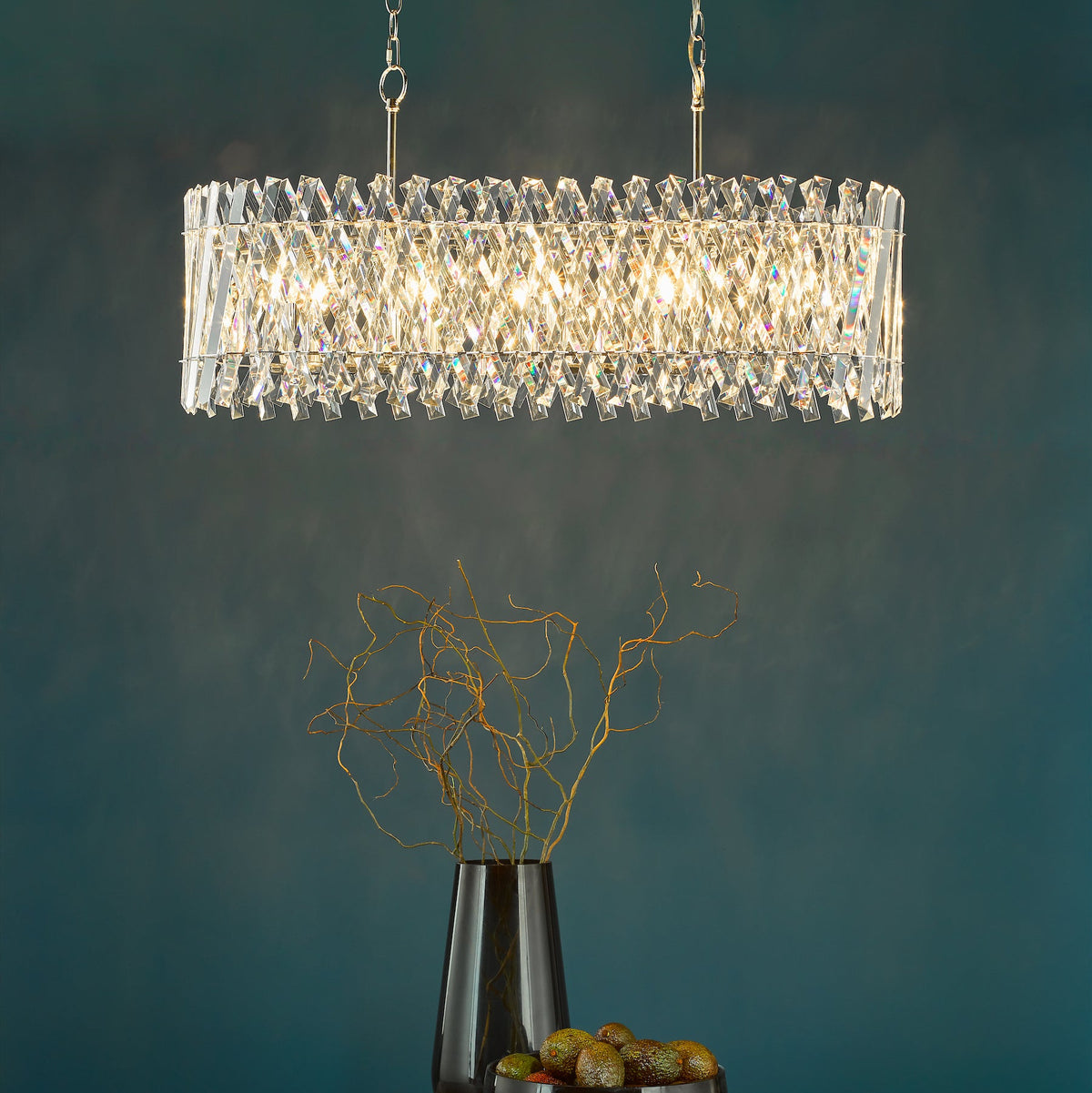 Rectangular crystal chandelier with a dark vase and avocados on a table
