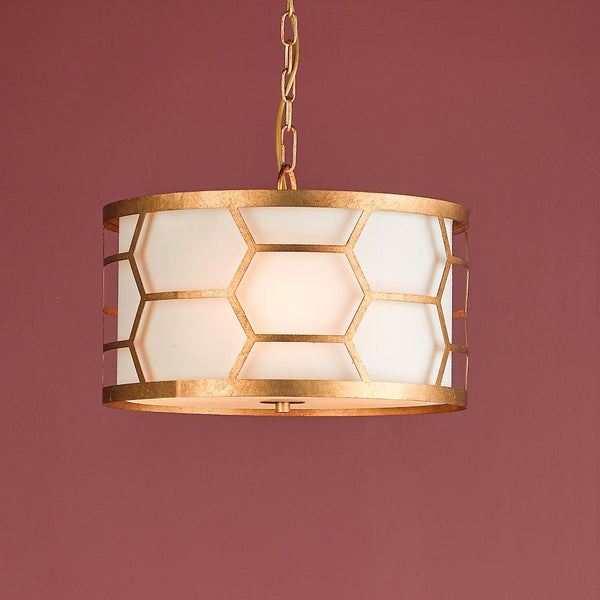 Gold pendant light with a white drum shade and a honeycomb pattern