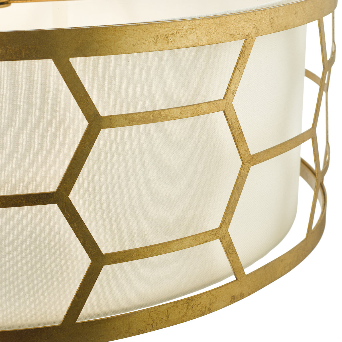 Close up of a gold metal lampshade with a geometric pattern and a white fabric lining
