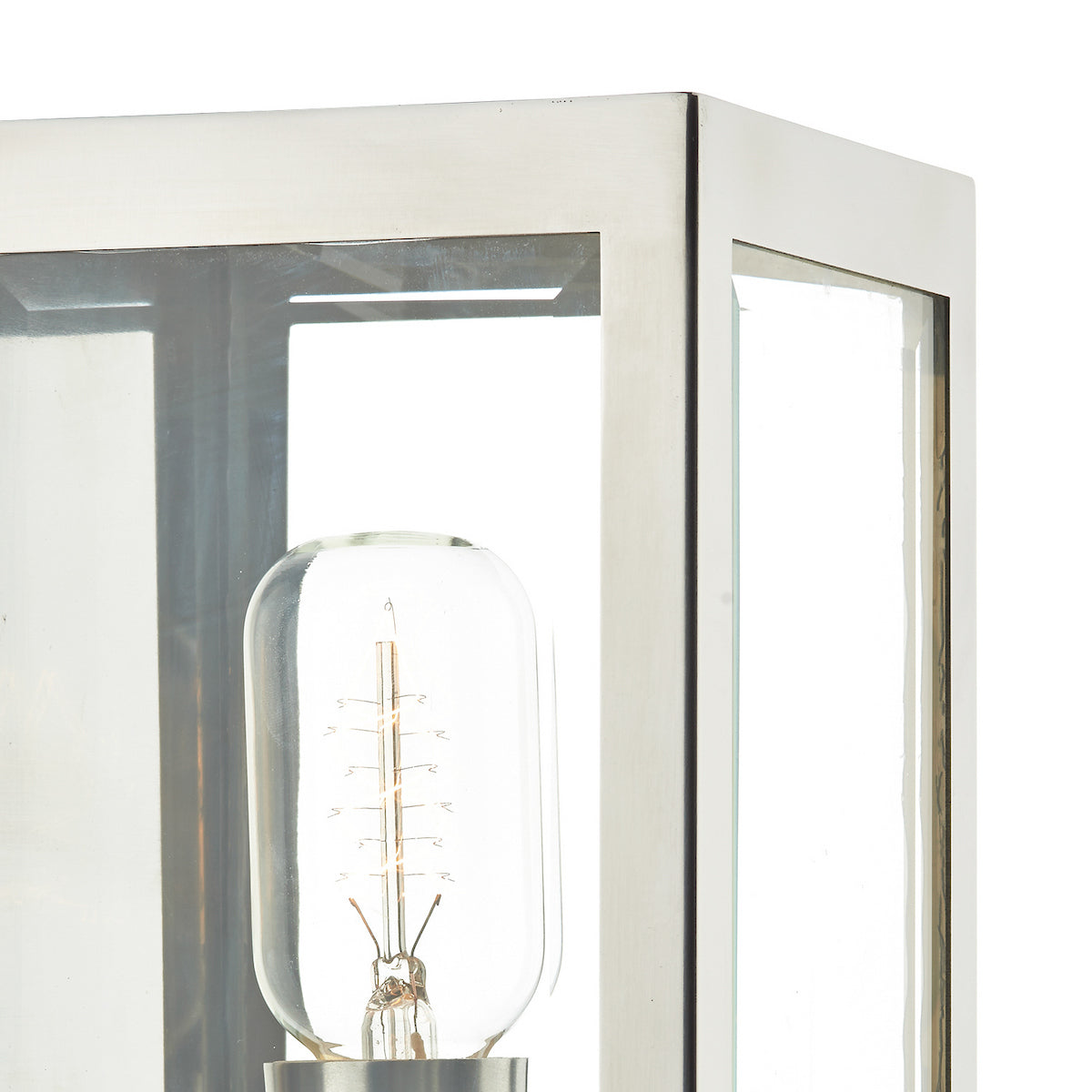 Close-up of a modern outdoor wall light with a clear glass panel and an exposed filament bulb.