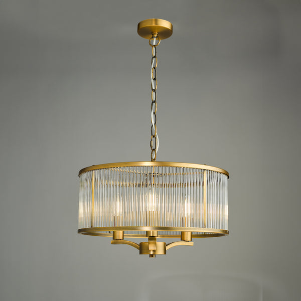 A gold chandelier with a cylindrical glass shade and three exposed bulbs.