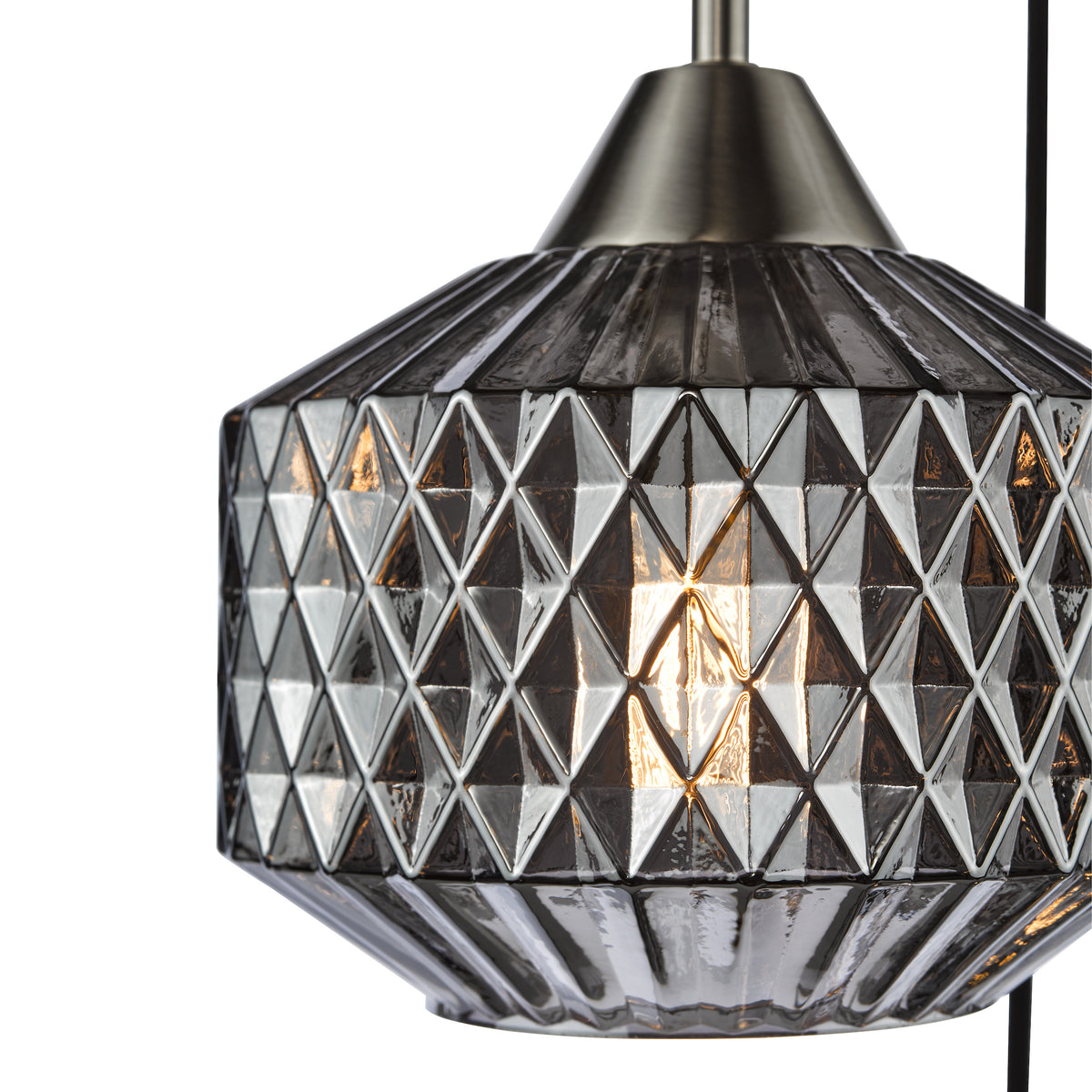 Close up of a pendant light with a geometric patterned glass shade and a brushed metal top