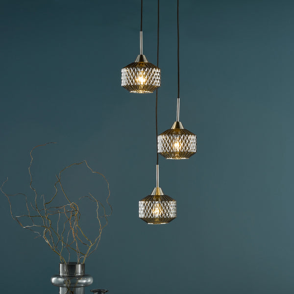 Three pendant lights with faceted glass shades hang against a dark teal wall