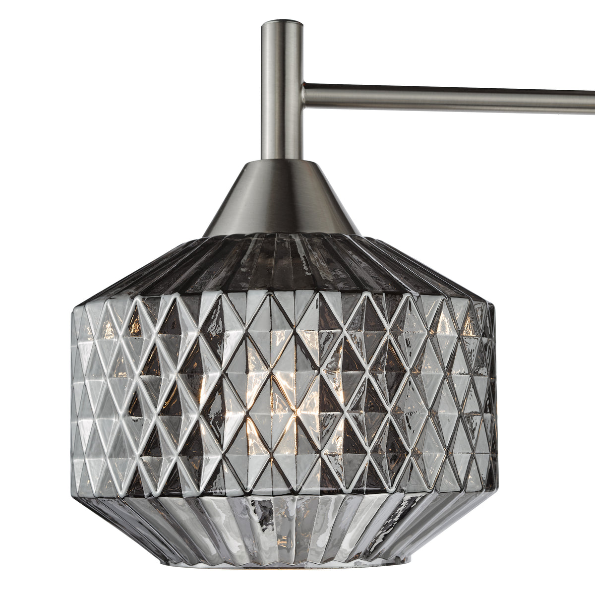 Close up of a brushed nickel light fixture with a faceted glass shade
