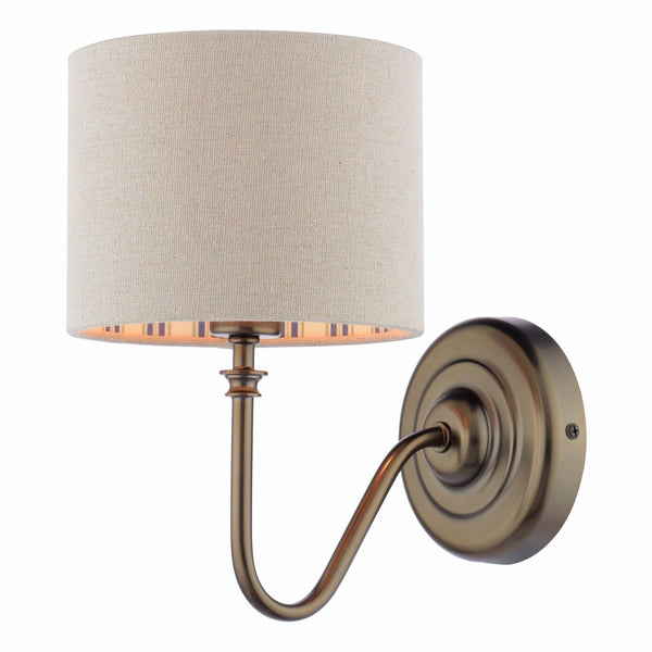 Antique brass wall sconce with a cylindrical beige fabric shade