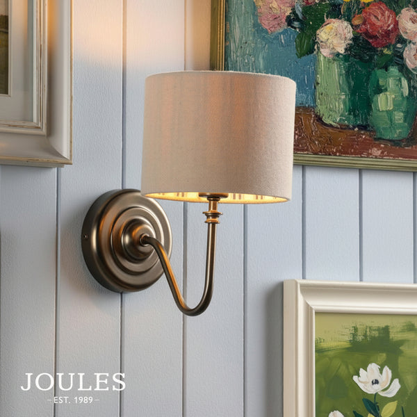 Joules Farley wall light in satin bronze with a natural linen shade mounted on a white panelled wall