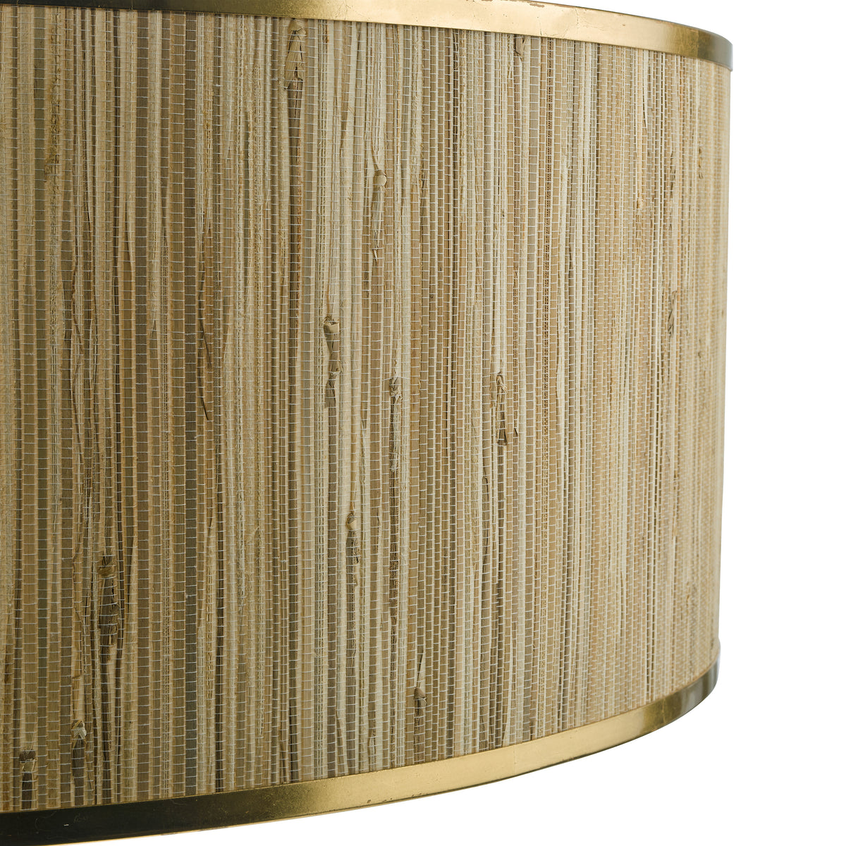 Close up of a lampshade with a woven grasscloth pattern in light brown and beige, framed by brass trim