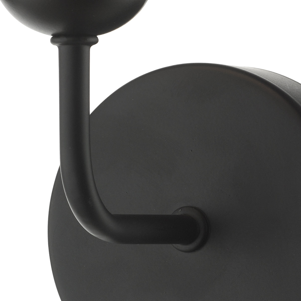 Close-up of a matte black wall sconce with a curved arm and round backplate.