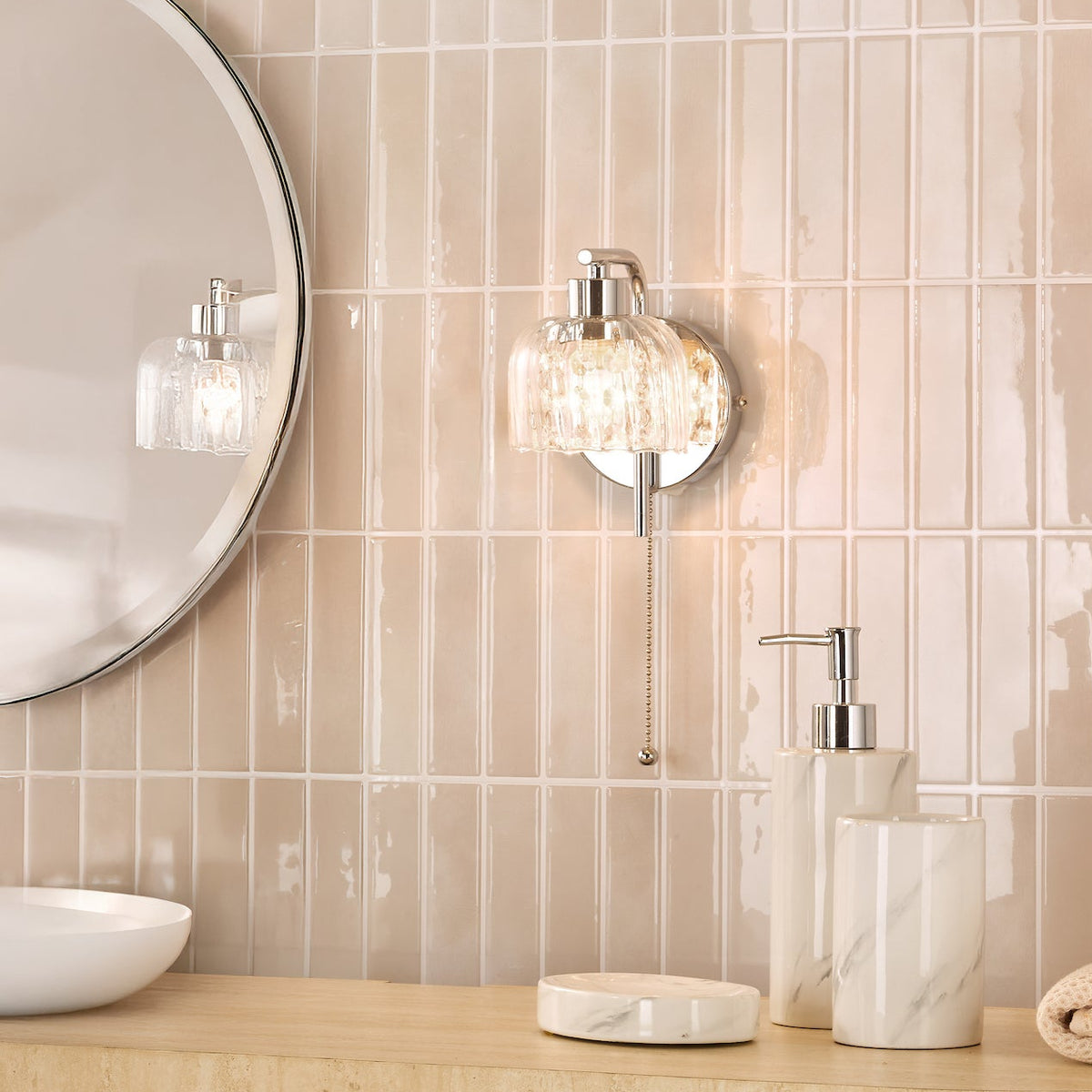 Bathroom with a round mirror, a wall light, and marble effect soap dispenser, tumbler, and soap dish