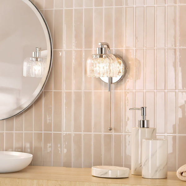 Bathroom with a round mirror, a wall light, and marble effect soap dispenser, tumbler, and soap dish