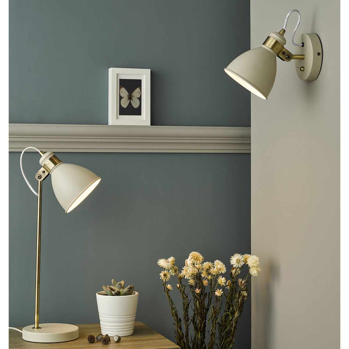Cream and brass table lamp and wall light with a framed butterfly picture and dried flowers