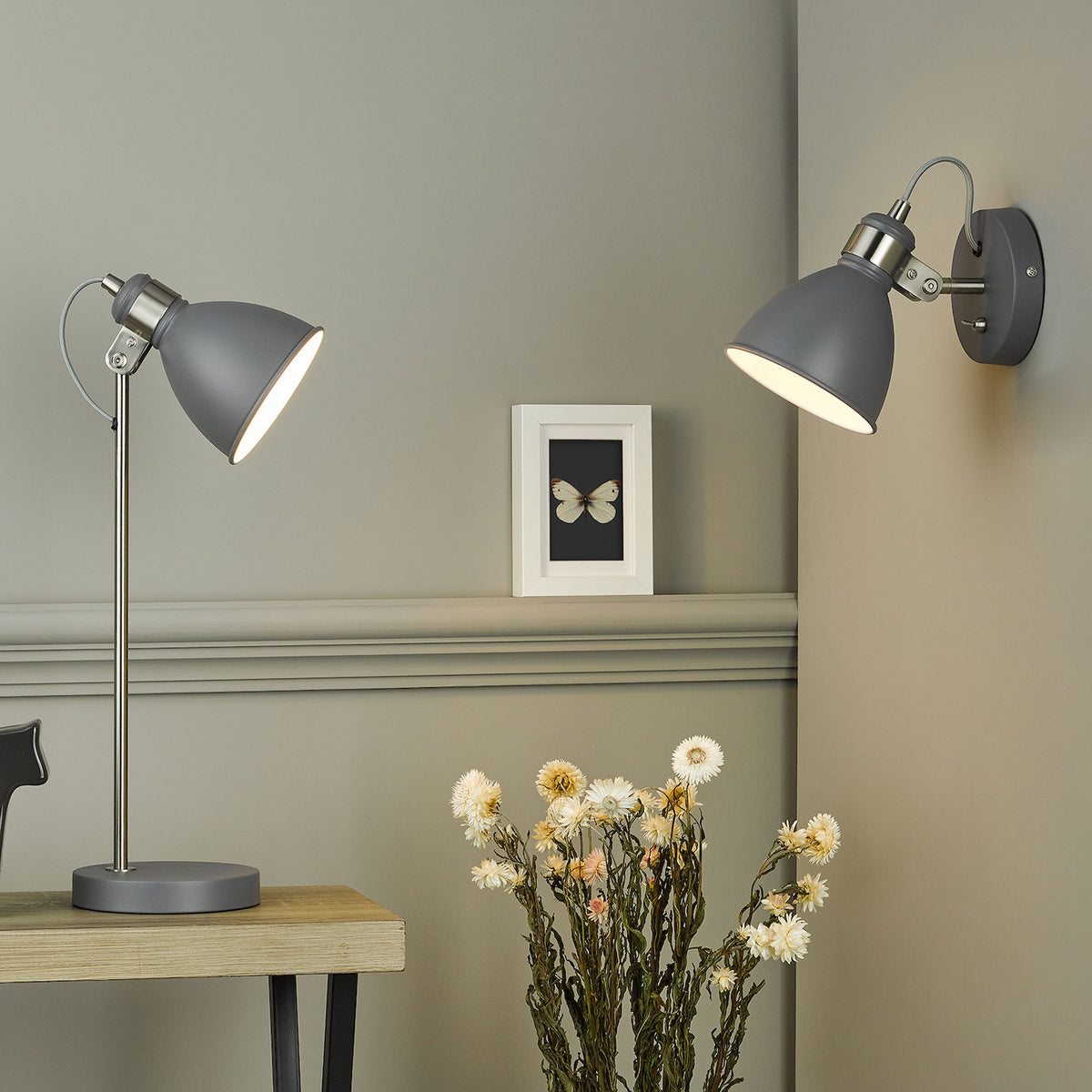 Two grey and chrome lamps, one a table lamp and one a wall light, illuminate a room with dried flowers