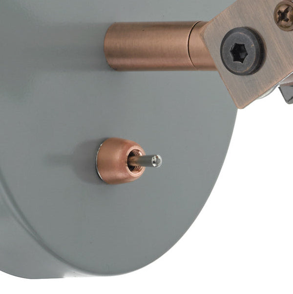 Close up of a copper toggle switch on a grey metal surface