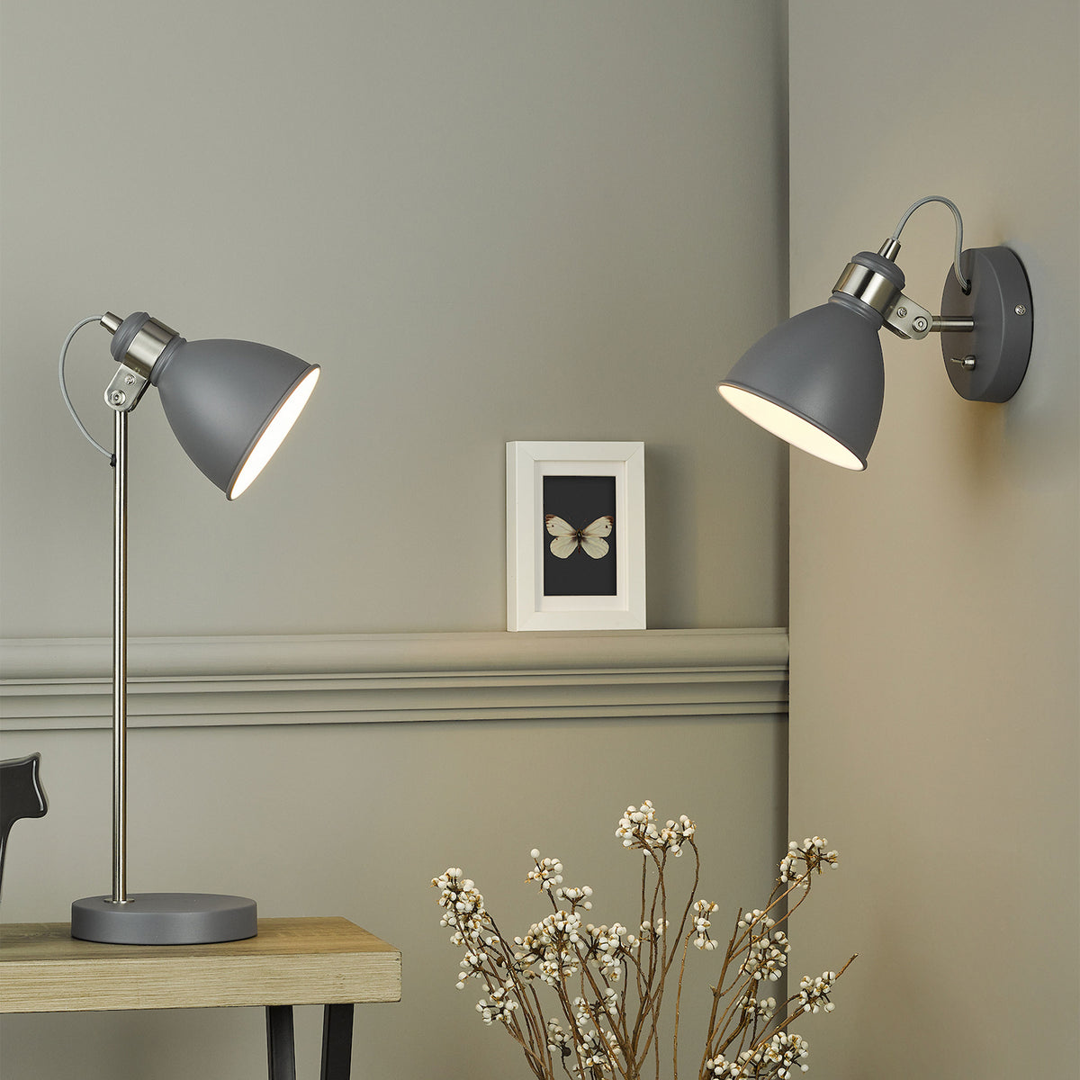Two grey and chrome lamps, one a table lamp and one a wall light, illuminate a grey room
