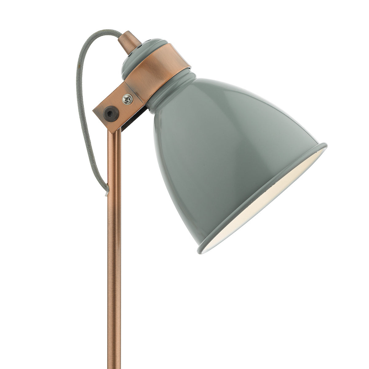 Close-up of a sage green metal lamp shade with a copper-colored arm and a gray fabric cord.