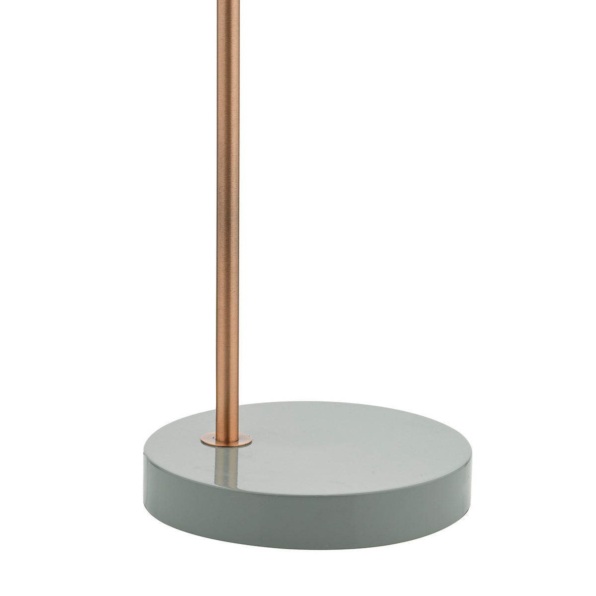 Close-up of a lamp base. A round, flat, sage green base supports a thin, copper-colored pole.