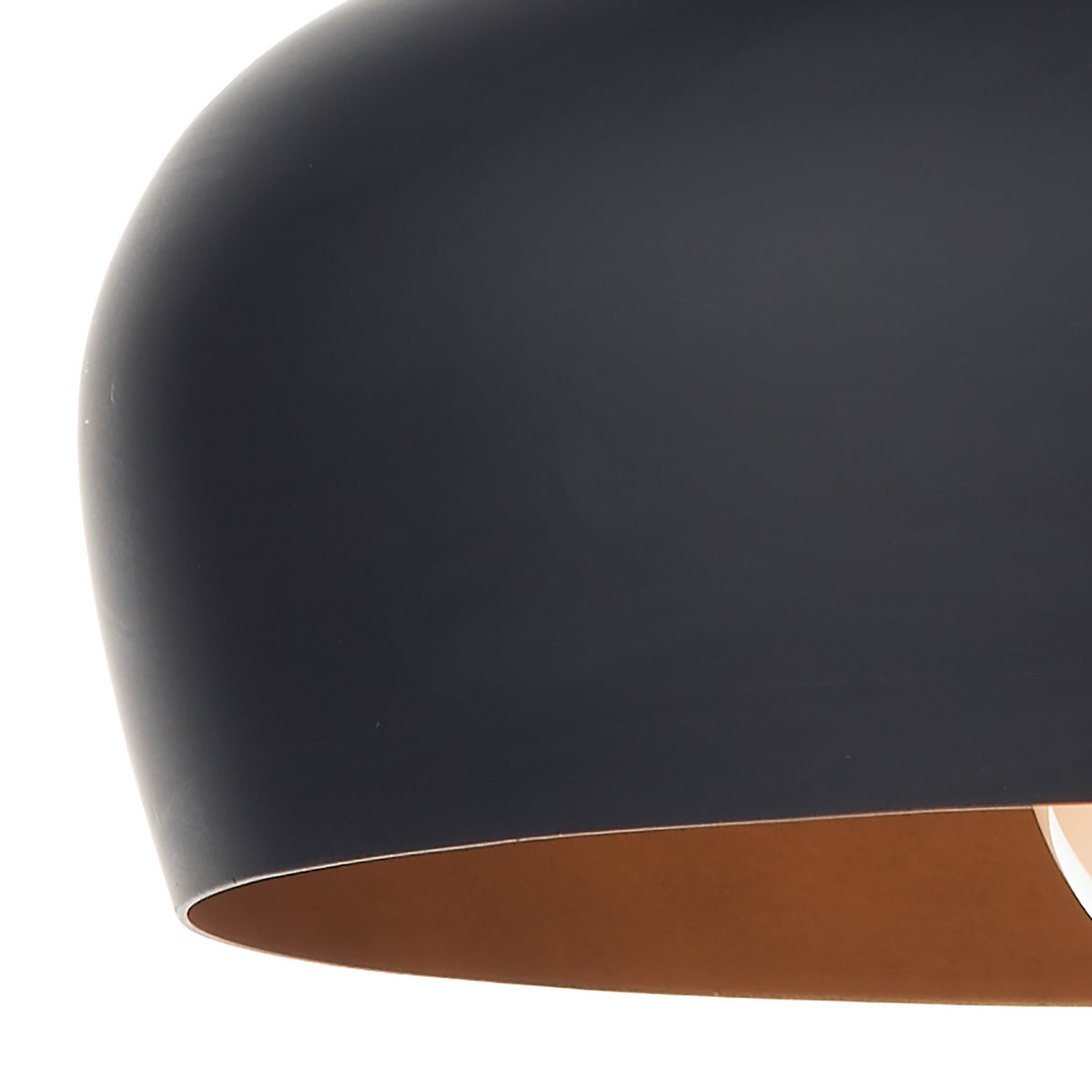 Close-up of a black pendant light with a copper interior.