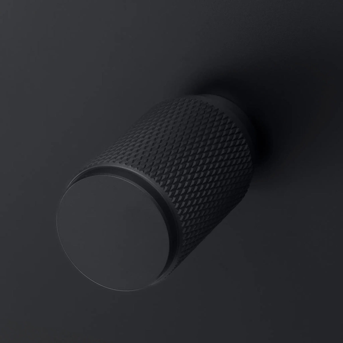 Matte black cylindrical knob with a textured diamond pattern on its side