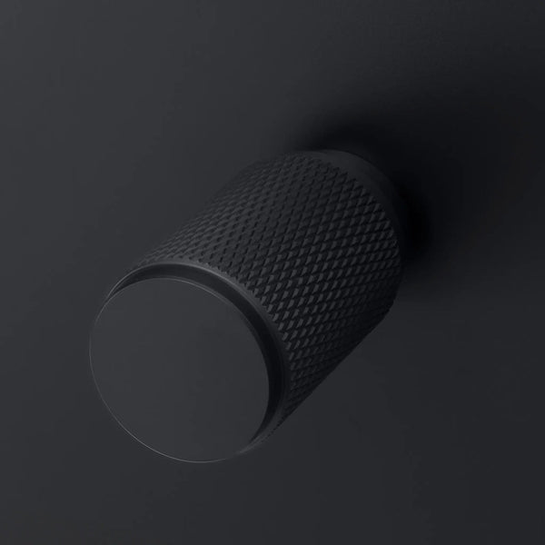 Matte black cylindrical knob with a textured diamond pattern on its side