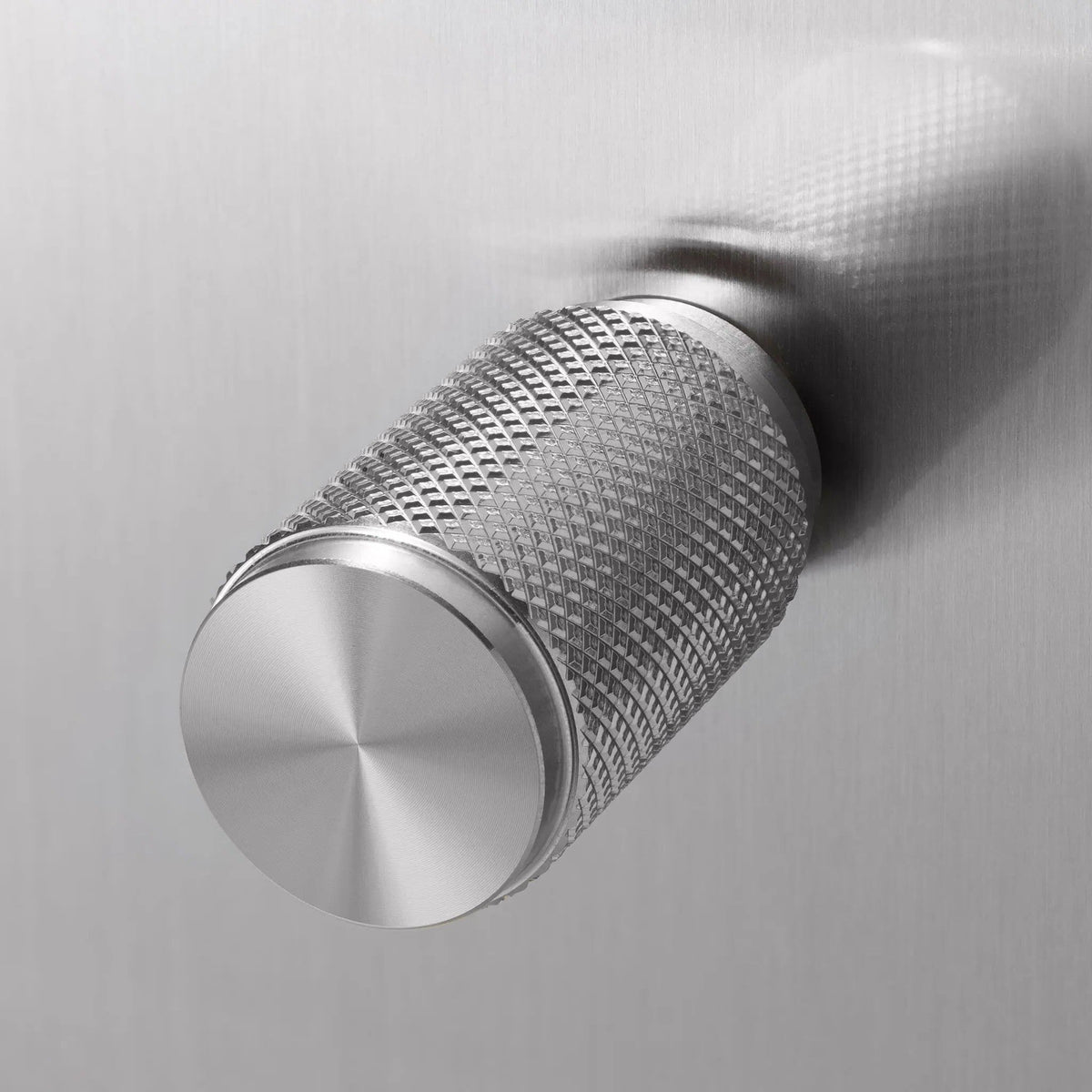 Close up of a silver metal knob with a diamond pattern texture