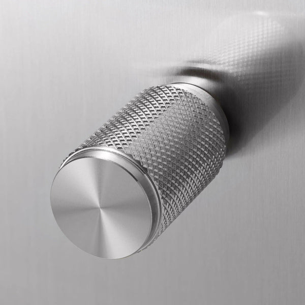 Close up of a silver metal knob with a diamond pattern texture