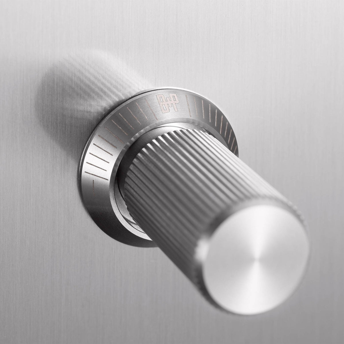 Close up of a silver metal knob with a textured surface and a logo on its base