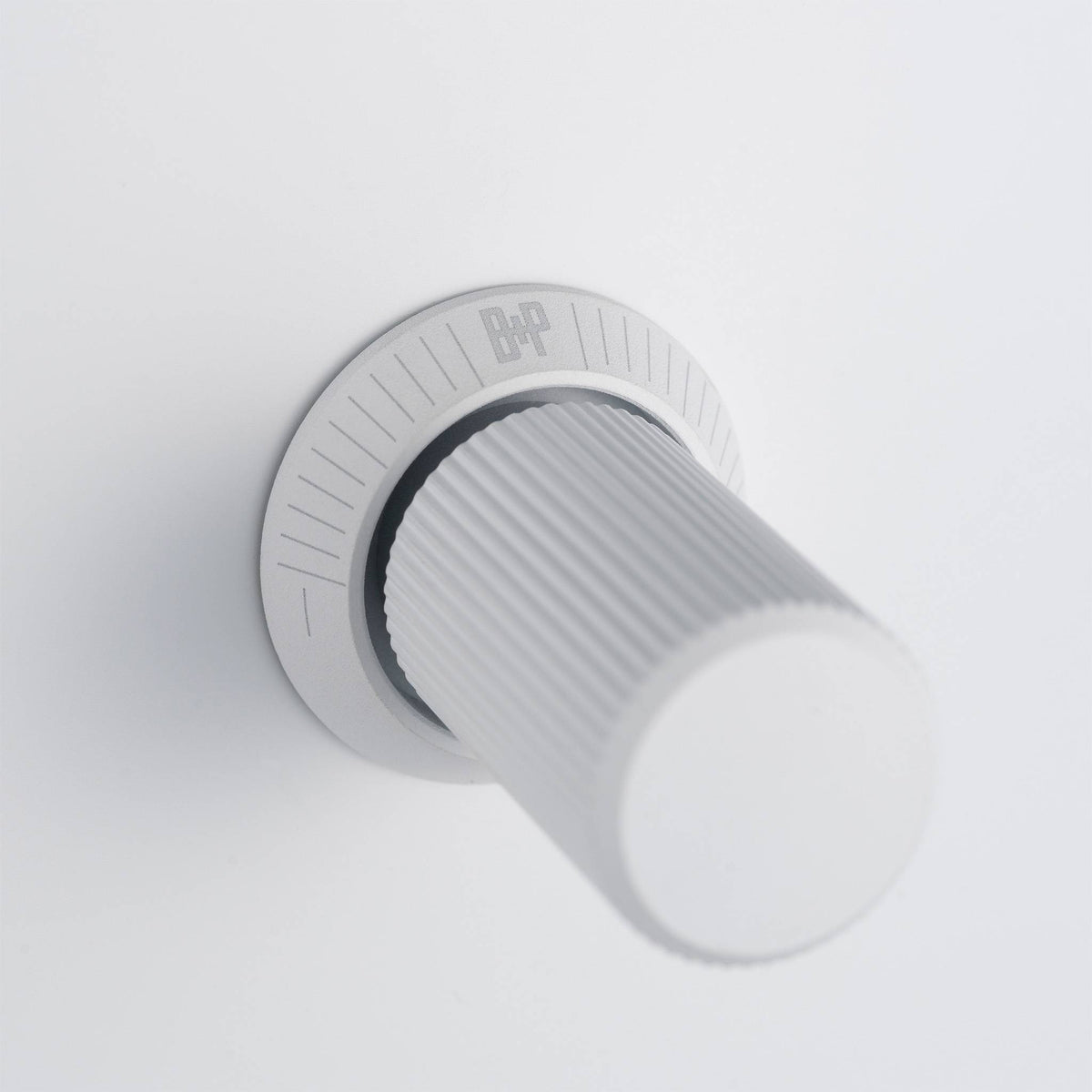 White volume control knob with a ridged texture and a circular base with markings