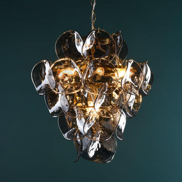 Chandelier with multiple clear glass petals and warm glowing bulbs against a dark teal background