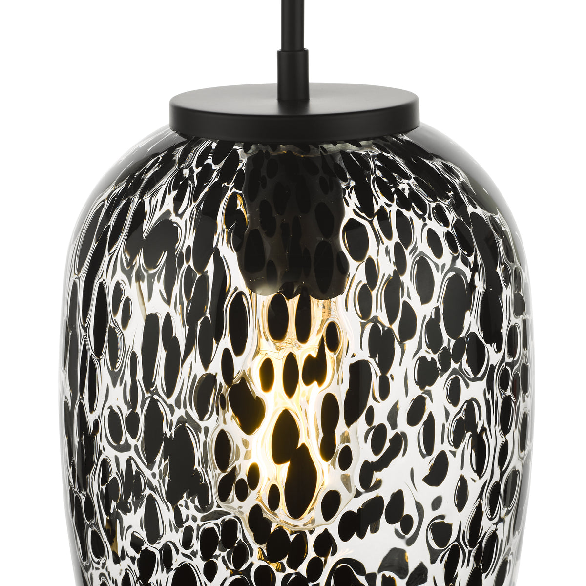 Close up of a black and white patterned glass pendant light with a glowing bulb inside