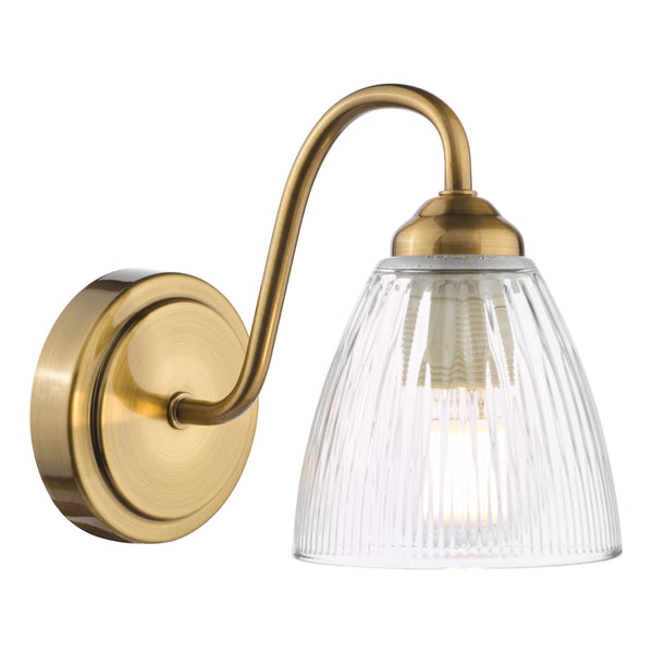 Brass wall light with a curved arm and a ribbed glass shade