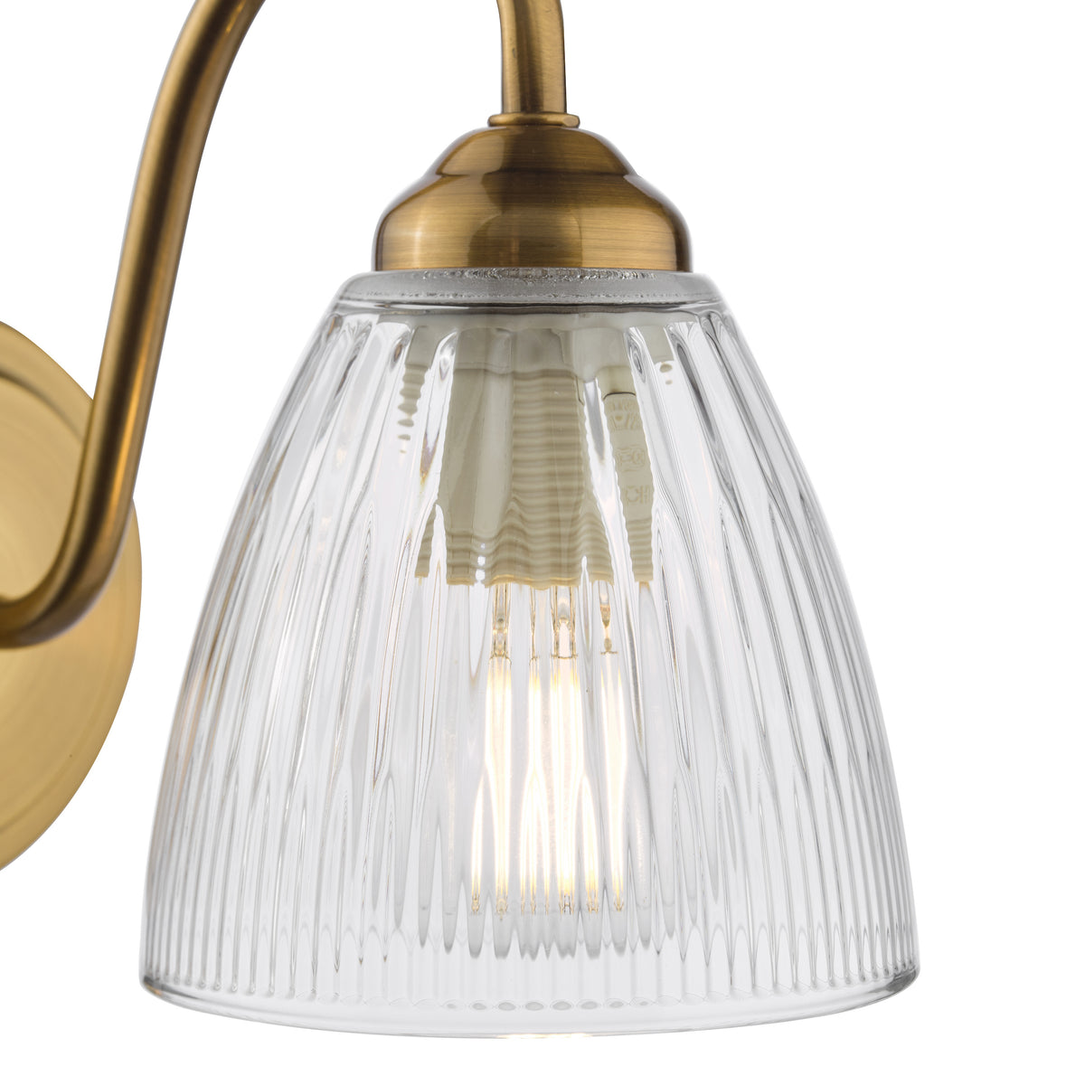 Close up of a brass wall light with a ribbed glass shade