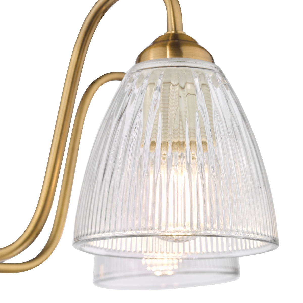 Close up of a brass chandelier arm with a ribbed glass shade and an illuminated bulb
