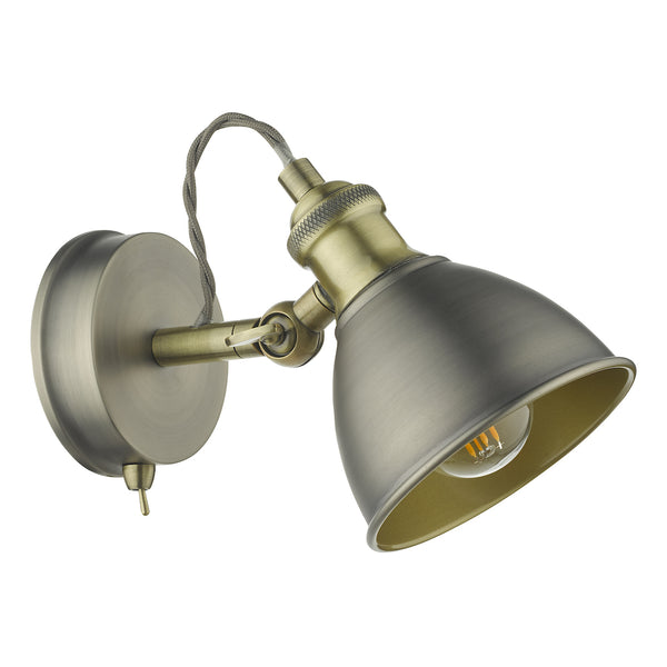 Antique brass wall light with a dome-shaped shade and exposed bulb.