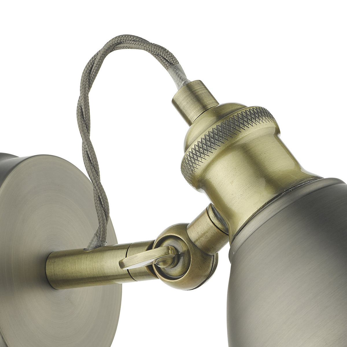 Close-up of an antique brass wall light with a grey braided cable and adjustable arm.