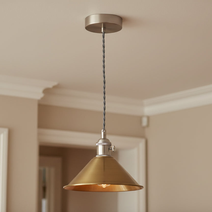 Brushed brass pendant light with a conical shade and a grey twisted fabric cable, against a white background.