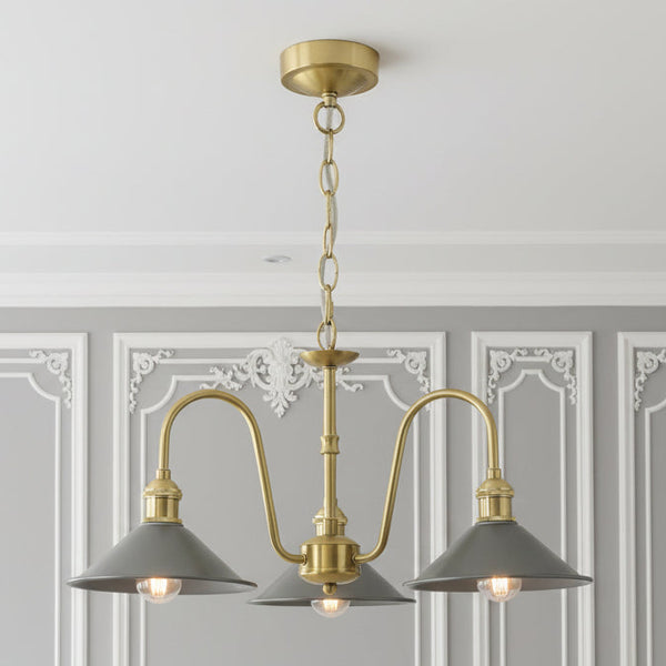 A brass chandelier with three arms, each holding a grey conical shade with an exposed light bulb.