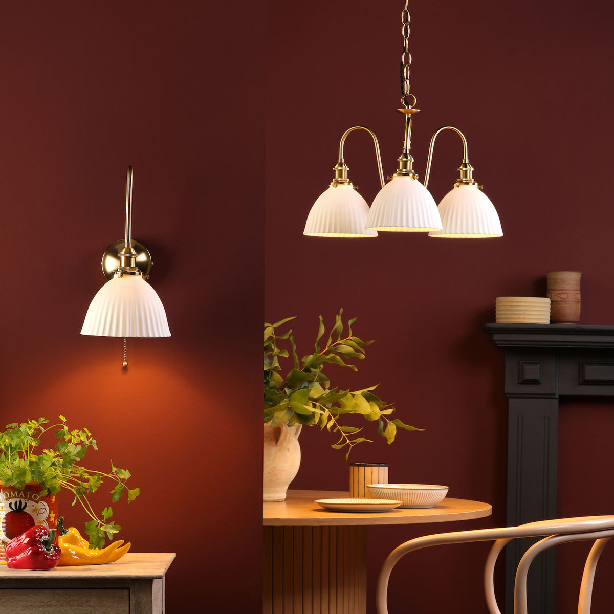 A wall sconce and a chandelier with white fluted shades and brass accents illuminate a dining area.