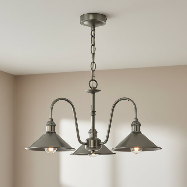 Antique brass chandelier with three downward-facing, cone-shaped shades and exposed bulbs.