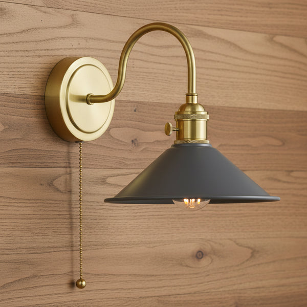 Brass wall sconce with a curved arm, a dark gray conical shade, and a pull chain switch. The light bulb is visible.