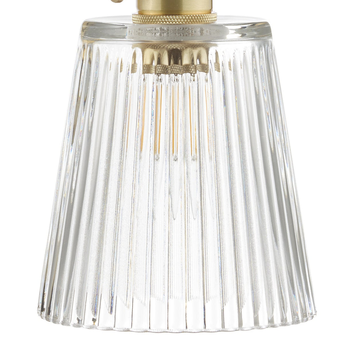 A brass wall sconce with a curved arm, a fluted glass shade, and a pull chain switch.