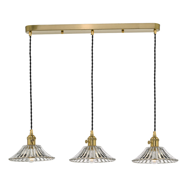 Three clear glass fluted pendant lights with brass fittings hang from a rectangular brass bar.