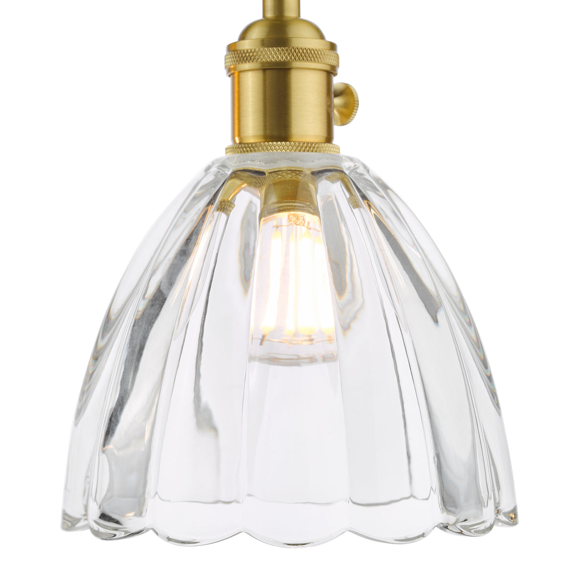 Close-up of a clear, fluted glass light shade with a brass fixture and an illuminated bulb.