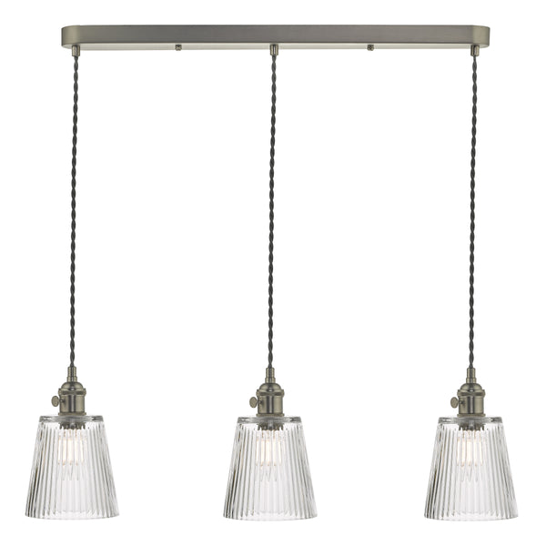 Three pendant lights with ribbed glass shades and antique brass fittings, hanging from a rectangular bar.
