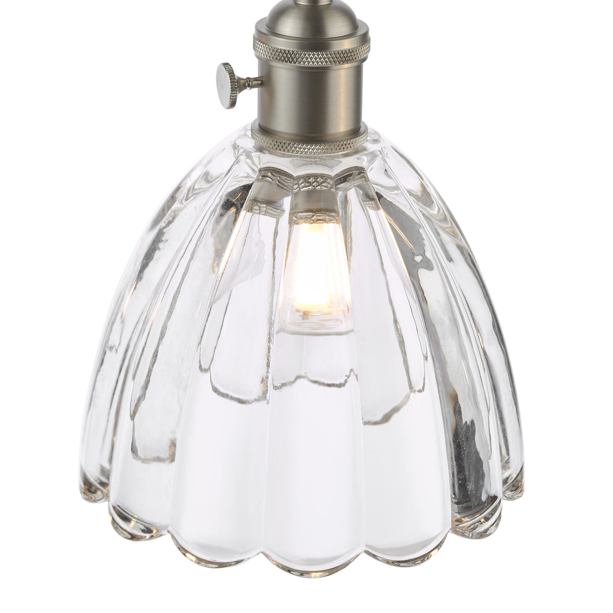 Close-up of a clear glass pendant light with a scalloped edge and a brushed nickel fixture, illuminated.