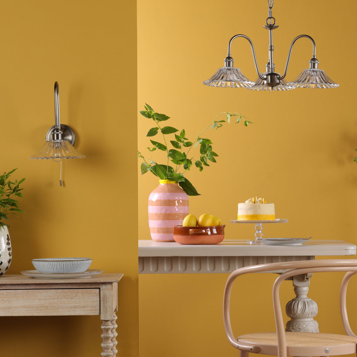 A wall sconce and chandelier with ribbed glass shades illuminate a room with yellow walls.