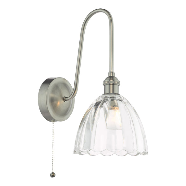 Brushed nickel wall light with a curved arm and a fluted clear glass shade, featuring a pull chain switch.