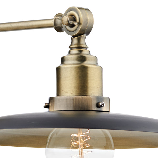 Close-up of a brass light fixture with a black shade and exposed filament bulb.