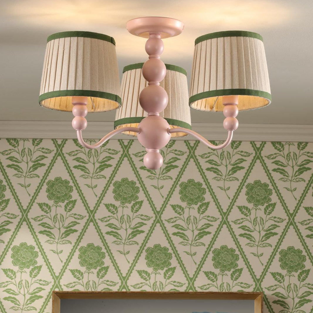 Pink three arm ceiling light with pleated beige shades and green trim